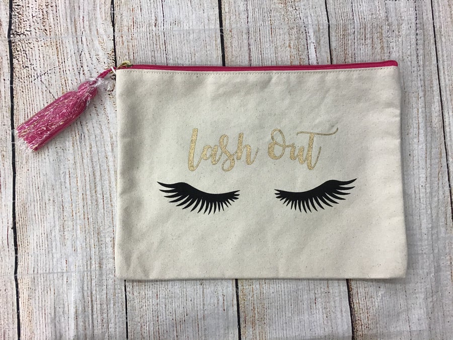 Mudpie Lash Out Canvas Makeup BagCanvas makeup bag with pink tassel on the zipper. Reads “lash out” in gold and cute black eyelashes.