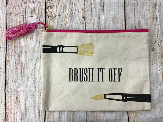 Mudpie Brush It Off Canvas Makeup BagCanvas makeup bag with pink tassel that reads “brush it off” with cute makeup brushes printed on the front.